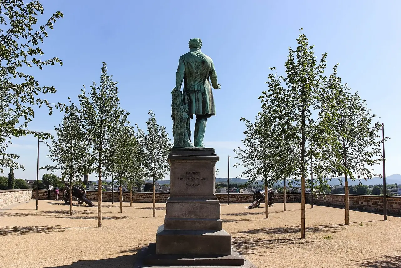 Bronzestandbild Ernst Moritz Arndts auf hohem Sockel zwischen jungen Bäumen auf dem Alten Zoll in Bonn