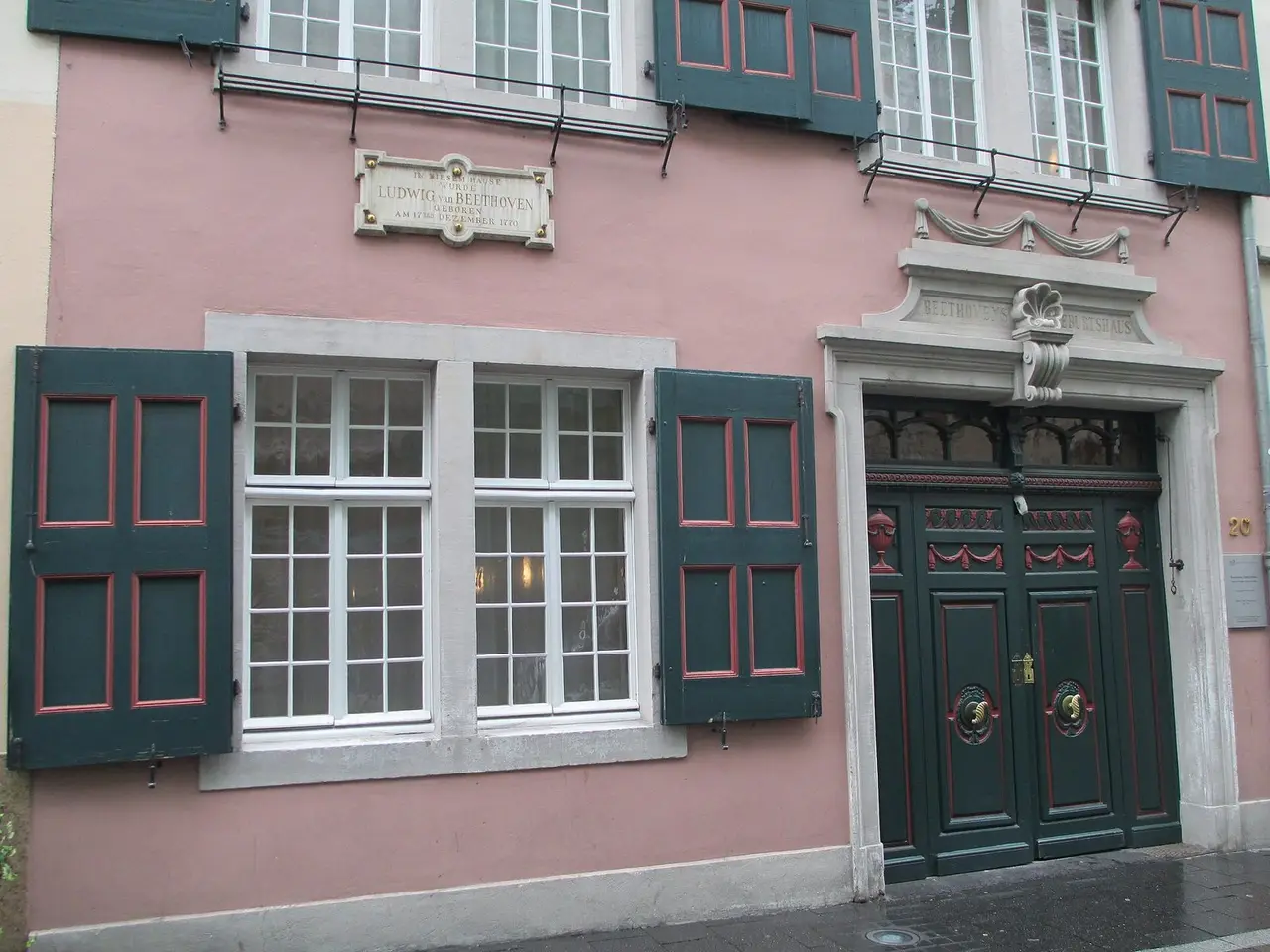 Rosafarbene Fassade des Beethoven-Hauses mit grünen Fensterläden, Gedenktafel und Eingangsportal