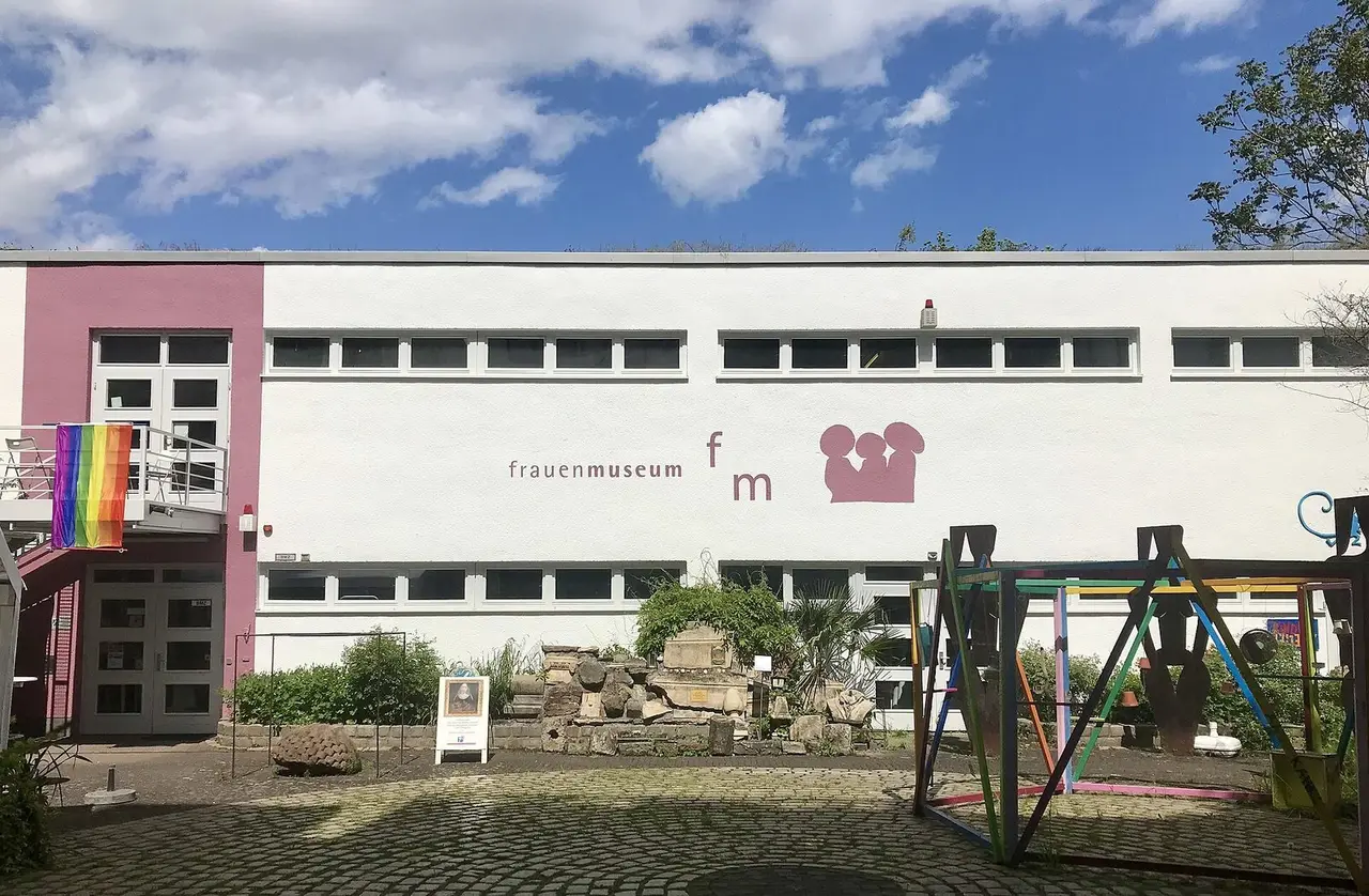 Weißes Museumsgebäude des Frauenmuseums mit Schriftzug und Kunstwerken im Innenhof