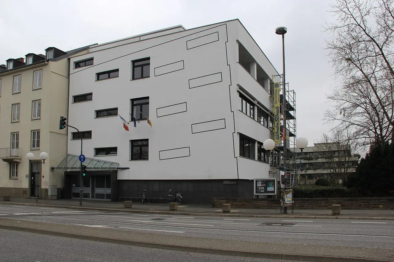 Weißes Gebäude des Institut français an der Adenauerallee 35 mit Glasvordach und Fahnen
