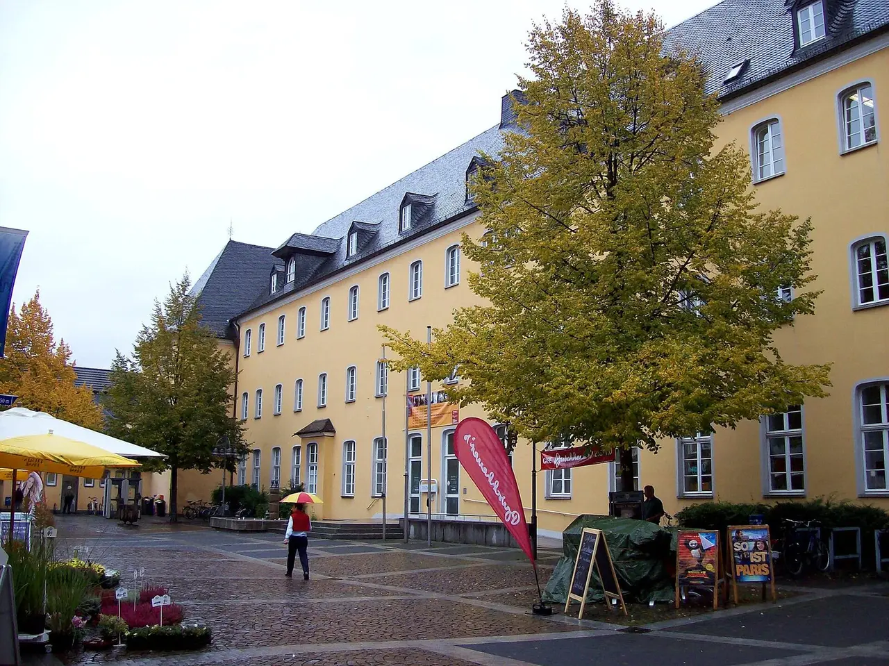 Gelbe Barockfassade des Brühler Rathauses mit Herbstbaum am Platz