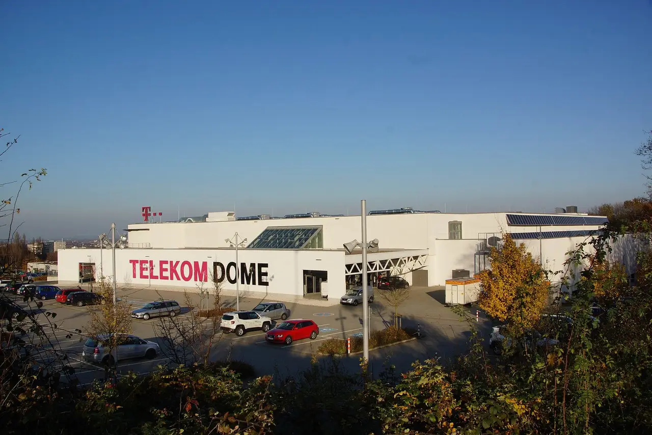 Weiße Halle des Telekom Dome auf dem Hardtberg mit Schriftzug und Parkplatz davor
