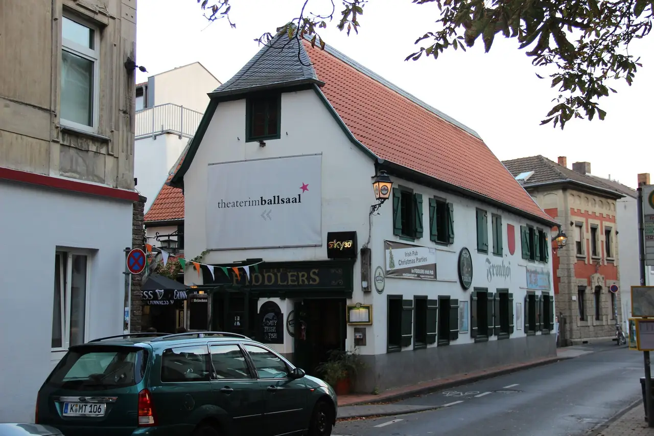 Weißes Giebelhaus mit rotem Dach, grünen Fensterläden und Schriftzug „theater im ballsaal“ an der Frongasse in Endenich