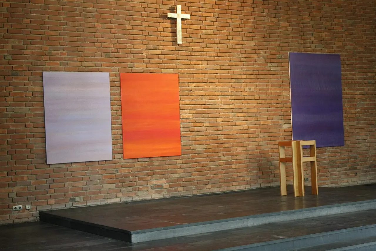 Backsteinwand mit Kreuz und drei farbigen Bildtafeln im Altarraum der Trinitatiskirche