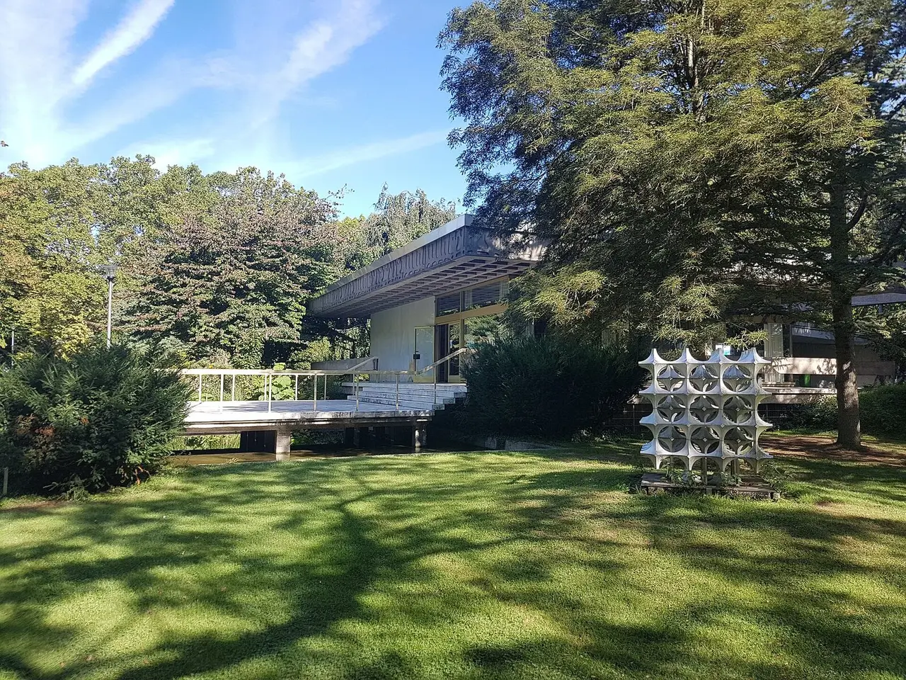 Flacher Trinkpavillon der Kurfürstenquelle mit Glasfront zwischen Bäumen im Bad Godesberger Kurpark